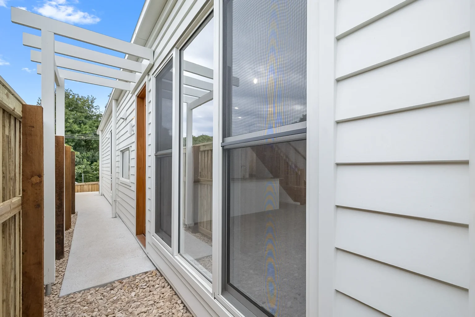 Narrow side passage beside an Arcadia home, with its windows looking straight onto the timber boundary fence