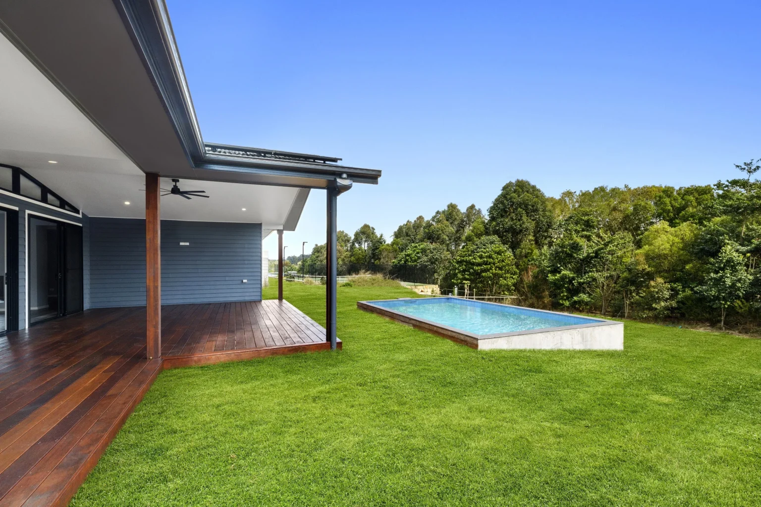 Timber deck of an Arcadia home at Diddillibah looking over a lawn that falls away to a pool and bushland